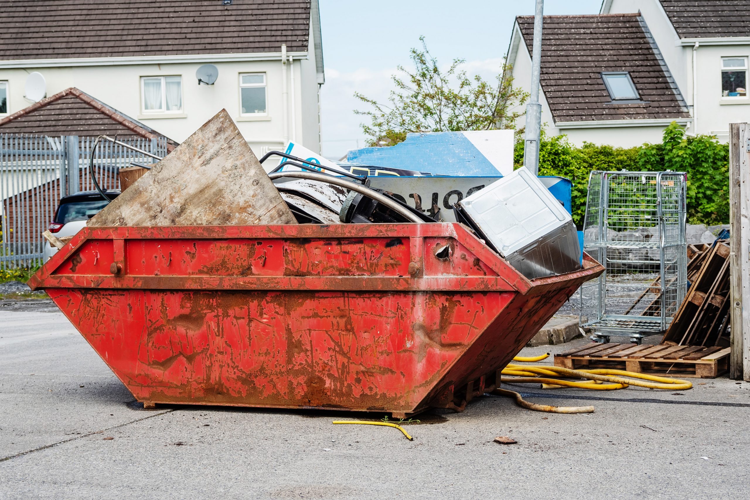 Red garbage removal skip full of rubbish and ready for collection in a street.